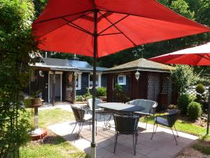 PottumFerienhaus Tanneneck的庭院里配有桌椅和红伞