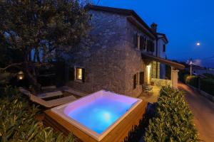 伊齐齐Villa Fani with Jacuzzi的夜间在房子前面的热水浴池