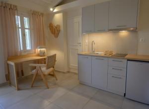 米蒂利尼奥基斯优雅小别墅酒店的厨房配有白色橱柜、桌子和书桌。