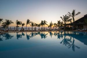 基济姆卡济Kwanza Resort by SUNRISE的棕榈树和日落的游泳池