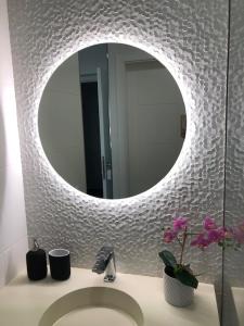 萨阿拉德洛斯阿图内斯Villa El Buzo的浴室配有带镜子和鲜花的盥洗盆