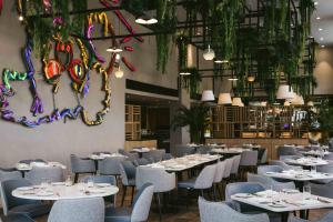 里斯本Martinhal Lisbon Oriente的一间设有白色桌椅的餐厅,种植了植物
