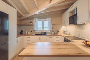 罗达Melena Premium Suites的厨房配有白色橱柜和木制台面