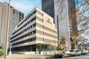 美因河畔法兰克福Premier Inn Frankfurt Westend的一座高大的建筑,前面有汽车停放