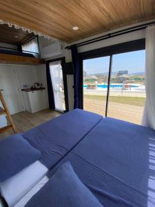 博阿齐奇Lavira Tiny House Village的一间卧室设有蓝色的床和大窗户