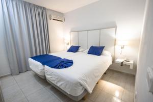 普拉亚布兰卡凯海滩太阳酒店的卧室配有带蓝色枕头的大型白色床