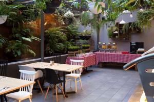 悉尼悉尼美罗阿斯皮尔酒店的一间设有桌椅的餐厅,种植了植物
