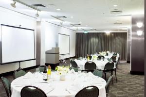 悉尼悉尼美罗阿斯皮尔酒店的一间会议室,配有桌椅和投影屏幕
