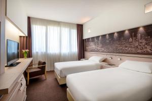 萨韦纳河畔圣拉扎罗UNAHOTELS Bologna San Lazzaro的酒店客房设有两张床和电视。