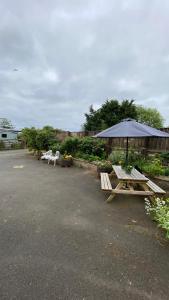 滨海索尔特本Wheelhouse - Grinkle Bell Cottage的停车场设有两张野餐桌和一把雨伞