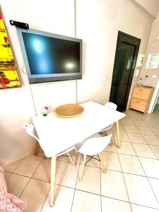 科莫蒂尼Sunny & Bright的一张带椅子的白色桌子和墙上的电视