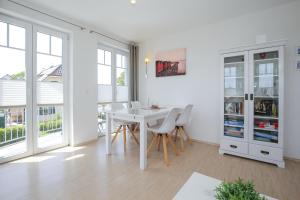 博尔滕哈根Achtern Diek Wohnung 14的白色的用餐室配有白色的桌椅