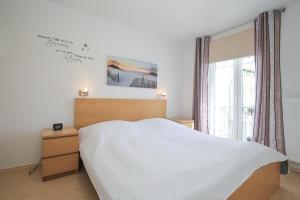 博尔滕哈根Achtern Diek Wohnung 14的卧室配有白色的床和窗户。