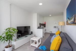 卡帕里卡海岸BeGuest Beachfront Apartment Caparica Lisbon的客厅配有蓝色的沙发和电视