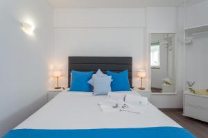 卡帕里卡海岸BeGuest Beachfront Apartment Caparica Lisbon的卧室配有带蓝色枕头的大型白色床