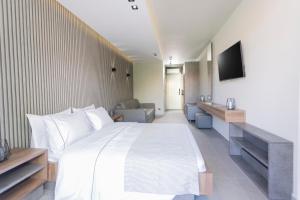 佩科霍里Notos Premium Holiday Apartments的卧室配有一张白色大床和电视。