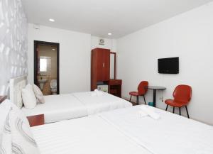 胡志明市Nguyen Thanh Hotel的配有两张红色椅子的酒店客房的两张床