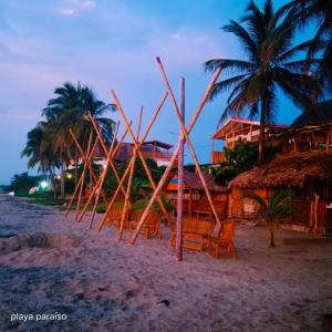 DibullaHotel Playa Paraiso的海滩上的一组椅子和棕榈树