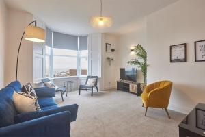 桑德兰5 Roker Terrace - Seaview apartments的客厅配有蓝色的沙发、椅子和电视