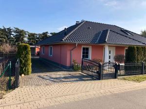 森夫滕贝格Seeliebe mit Sauna und nur 50 mtr. bis zum Strand的粉红色的房子,前面有栅栏
