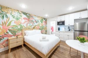 加尔维斯敦Pastel Tropics Studio Apartment的一间卧室配有一张带热带壁纸的大床