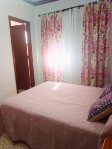 丰卡连特德拉帕尔马Pensión Los Volcanes的一间卧室配有一张带粉红色床单和窗帘的床