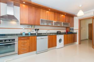 塔维拉Casa Mergoux - Maravilhoso Apartamento em Tavira的厨房配有木制橱柜、洗衣机和烘干机