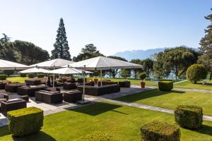 洛桑洛桑美岸皇宫大酒店的公园内带桌子和遮阳伞的庭院