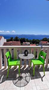 波尔Apartments Ivka Bol的阳台配有一张桌子和两张绿色椅子