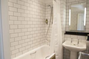 多尔盖罗皇家船艇酒店的白色瓷砖浴室设有水槽和浴缸