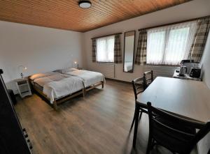 Le Paquier伯恩奥伯格布奈酒店的卧室配有床、桌子和窗户。