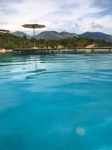萨兰达Botë Farms Agriturismo的一个带遮阳伞的大型蓝色海水游泳池