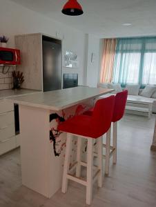 多列毛利诺斯TORREMOLINOS CENTER ESTUDIO Sun & Beach的厨房配有柜台和2把红色椅子