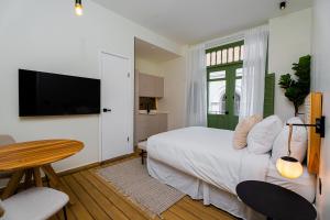 巴拿马城AmazINN Places Hotel Boutique Casa Marichu的一间卧室配有一张床、一张桌子和一台电视。