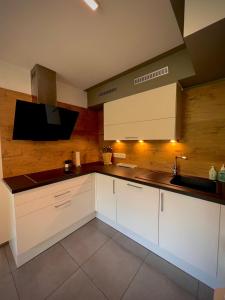 阿特湖畔翁特拉赫Apartment Ferienwohnung DAS UNTERACH am Attersee的一间带白色橱柜和水槽的厨房以及一台电视。