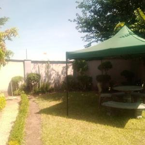卢萨卡Samkab Legacy & comfort Ndeke (airport)的院子里的桌子和遮阳伞