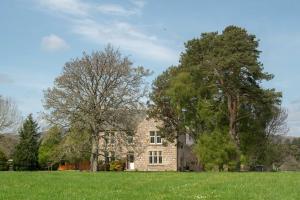 卡布里奇Feith Mhor Lodge的一座大石头房子,在田野里种有树木