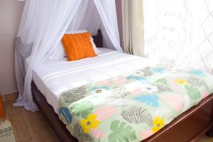VoiIlala House, Voi - 2 bed, 2 bath的床上的被子和橙色枕头