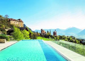 思科纳Hotel Finkennest - Panoramic Garden Resort的一座带城堡和山脉的游泳池