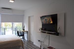 布宜诺斯艾利斯@juanbjustoapartamento的一间卧室配有一张床,墙上配有电视