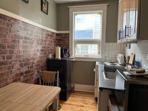 温尼伯Maryland Homestay in Winnpeg downtown的厨房设有砖墙和桌子