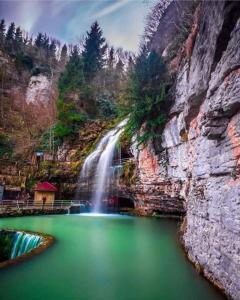 DüzköyUZUNALİ DAĞ EVİ的山前绿色湖泊上的瀑布