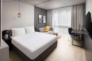 欧普菲康Radisson Hotel & Suites Zurich的卧室配有一张白色大床和一张书桌