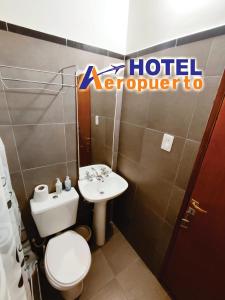 PericoHotel AEROPUERTO Jujuy的浴室设有卫生间水槽和酒店翻译标志