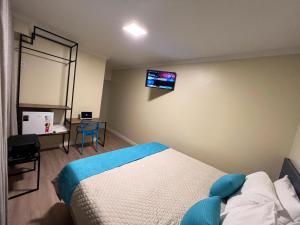 巴西利亚Hotel Suntuoso的卧室配有一张床,墙上配有电视。