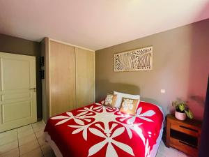 AtiueVahinerii Cosy Apt Tahiti的卧室配有红色和白色的床和门