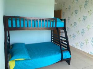 圣卡洛斯Lujoso y Familiar Apartamento de Playa y Golf en San Carlos Panamá的双层床配有蓝色床单和梯子
