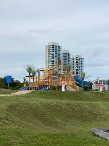 圣卡洛斯Lujoso y Familiar Apartamento de Playa y Golf en San Carlos Panamá的公园内一座游乐场,有建筑背景