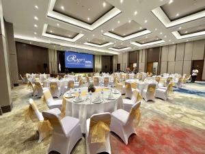 PinelengRogers Hotel Manado的一个带白色桌子和白色椅子的大型宴会厅