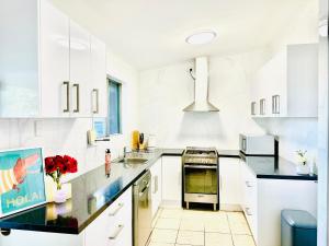 艾利斯斯普林斯Grabber- Three bedroom charm in Alice Springs的厨房配有白色橱柜和黑色台面